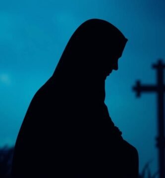 Obraz przedstawiający sylwetkę kobiety modlącej się w ciemności