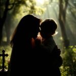 Ujęcie z góry przedstawiające matkę trzymającą dziecko na rękach, na tle lasu, po obu stronach którego stoi krzyż i świece.