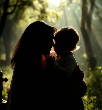 Ujęcie z góry przedstawiające matkę trzymającą dziecko na rękach, na tle lasu, po obu stronach którego stoi krzyż i świece.