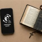Obraz telefonu komórkowego obok otwartej Biblii z różańcem pośrodku
